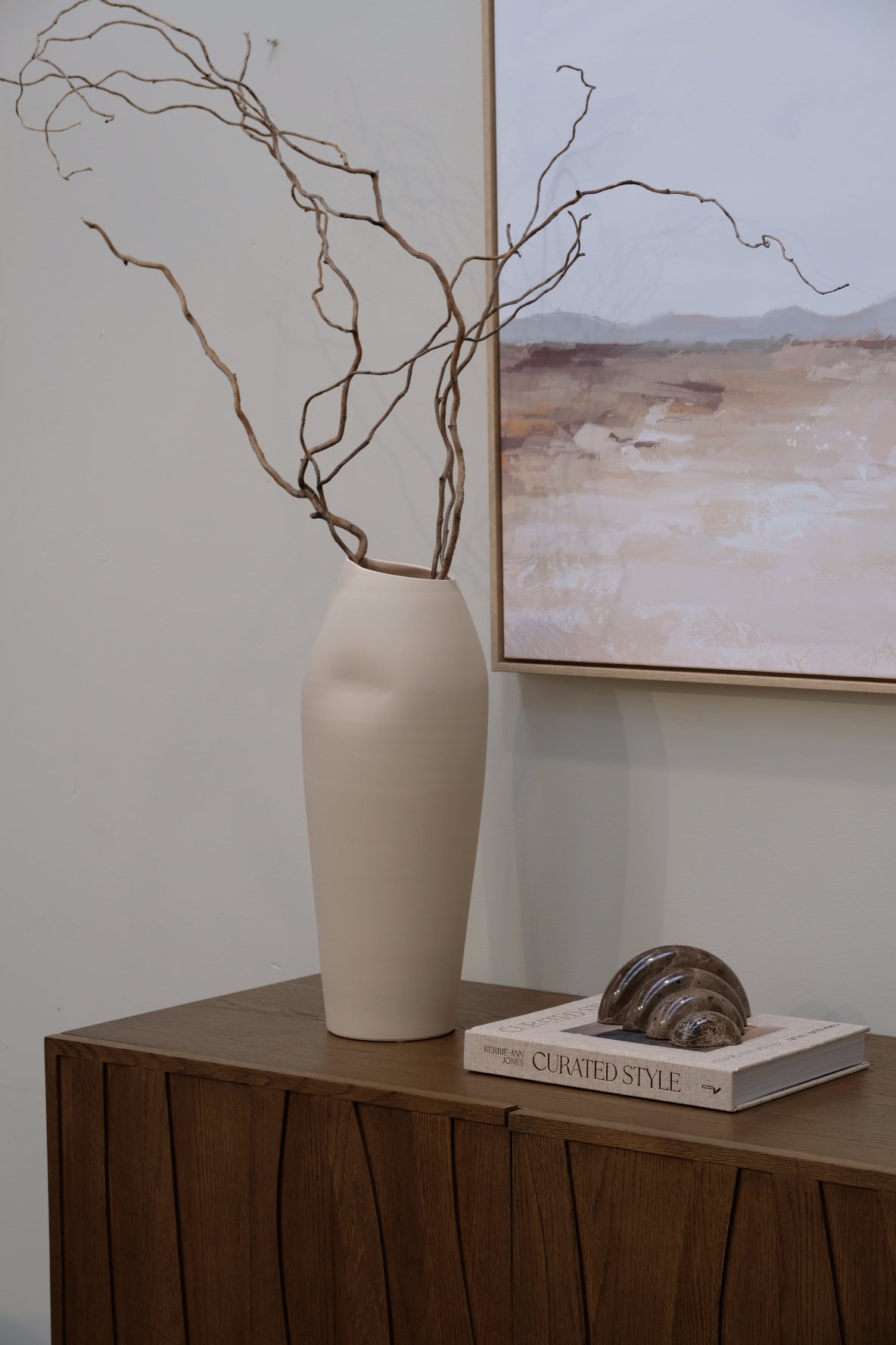 Decorative lamp with a branch on a shelf against a white wall